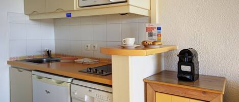 Una cocina compacta con microondas, cafetera y lavavajillas.