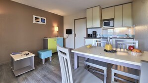 A compact kitchen with a dining area, a microwave, a coffee maker, and a small refrigerator. - Pierre & Vacances Résidence Eguzki (Saint-Jean-de-Luz)