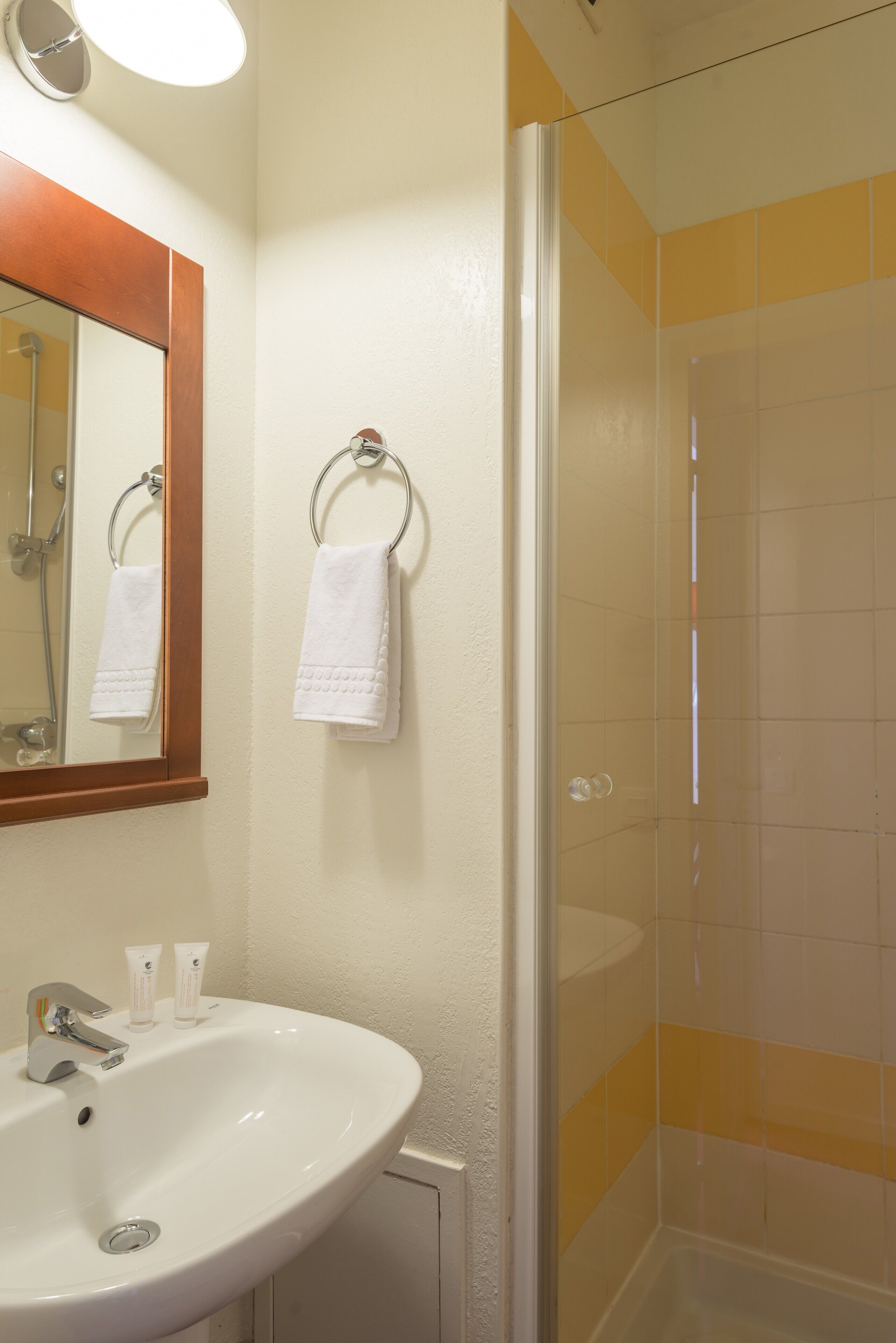 A bathroom with a white sink, a mirror, and a shower.