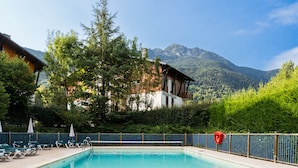 A swimming pool with lounge chairs and a mountain backdrop.