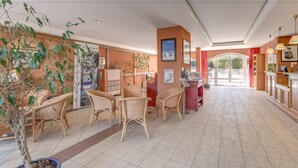 A spacious lobby with wicker furniture, a potted plant, and a view of the outdoors through a large window.