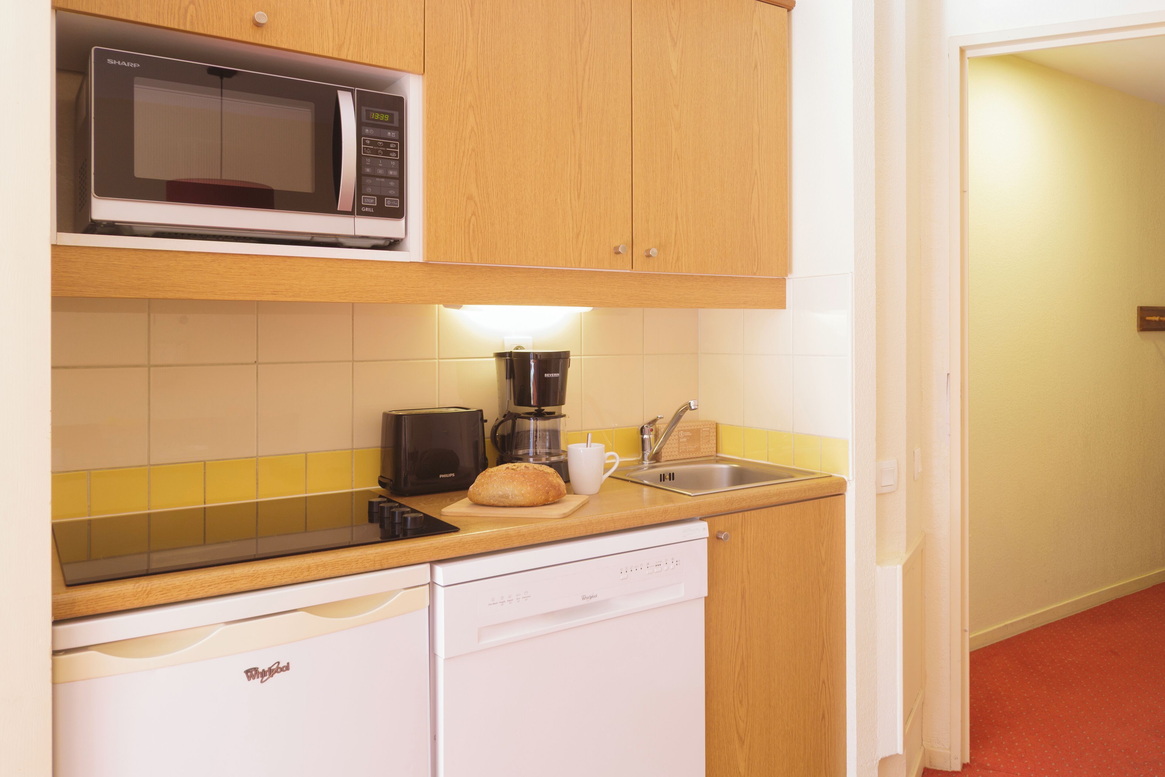 Una cocina compacta equipada con microondas, cafetera y lavavajillas.