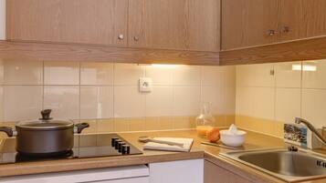 Una cocina con gabinetes de madera, estufa, pileta y salpicadero azulejado.