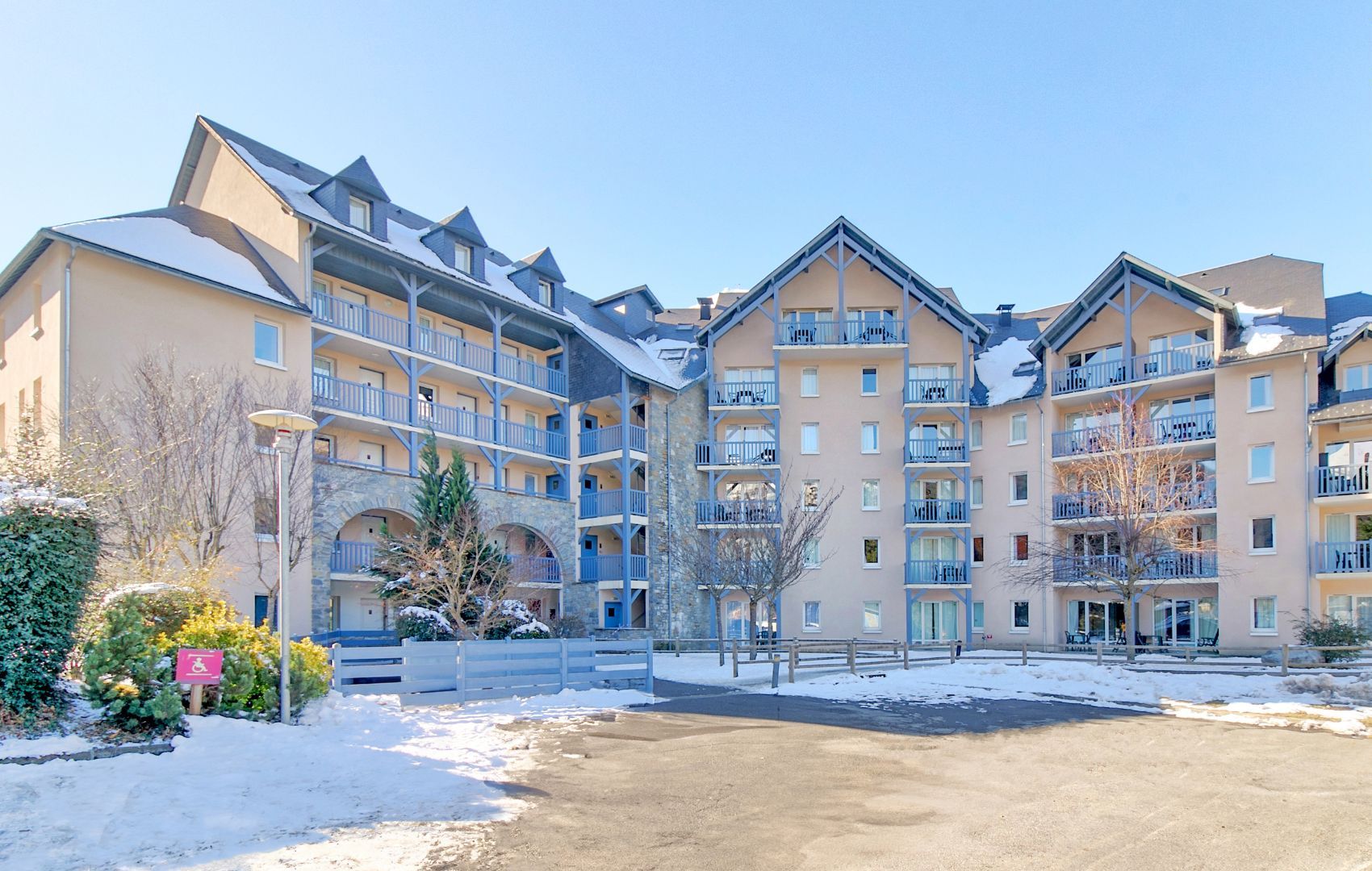 A multi-story hotel with balconies, a covered parking area, and snow on the ground.