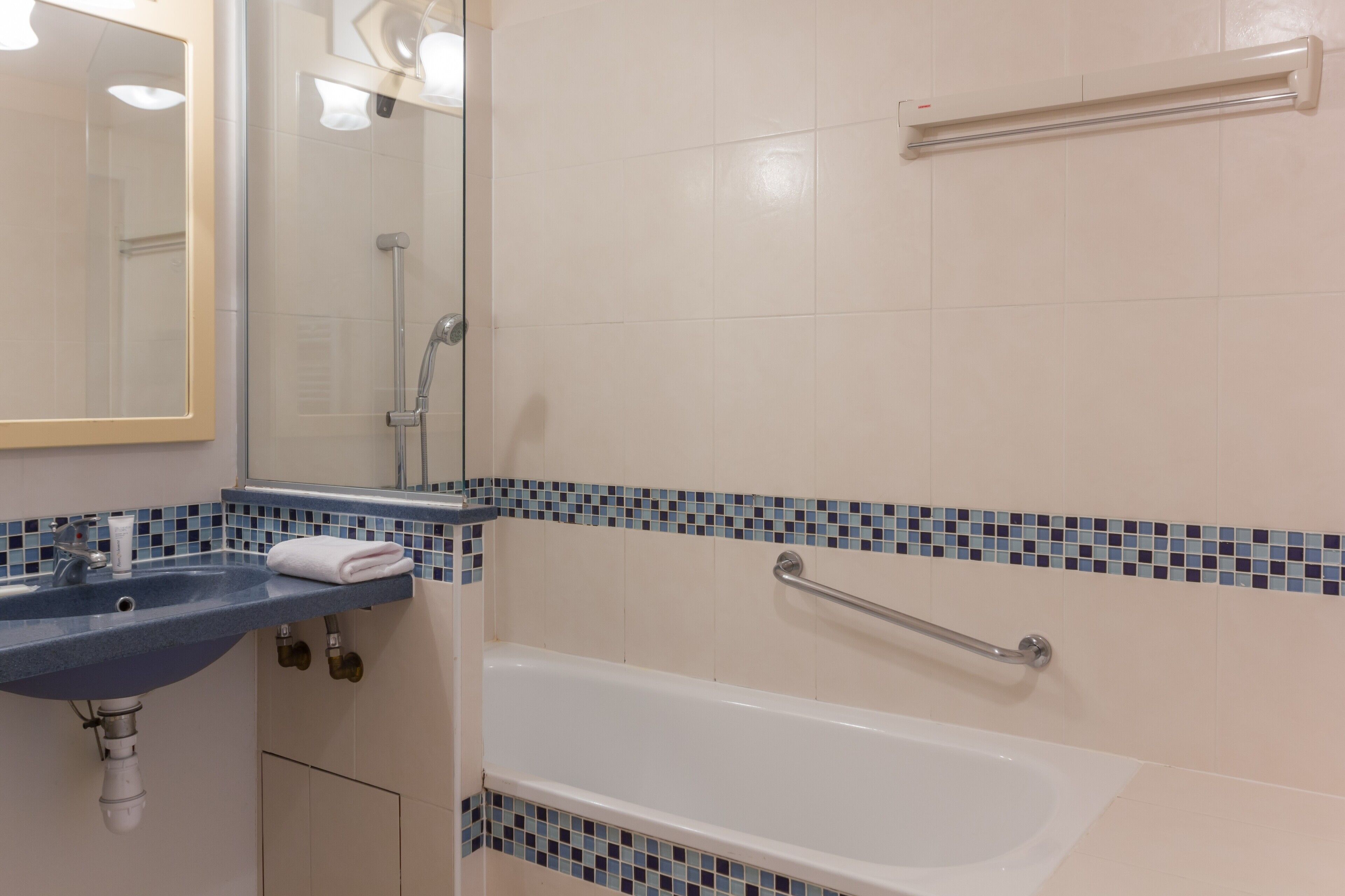 A bathroom with a sink, mirror, and bathtub.