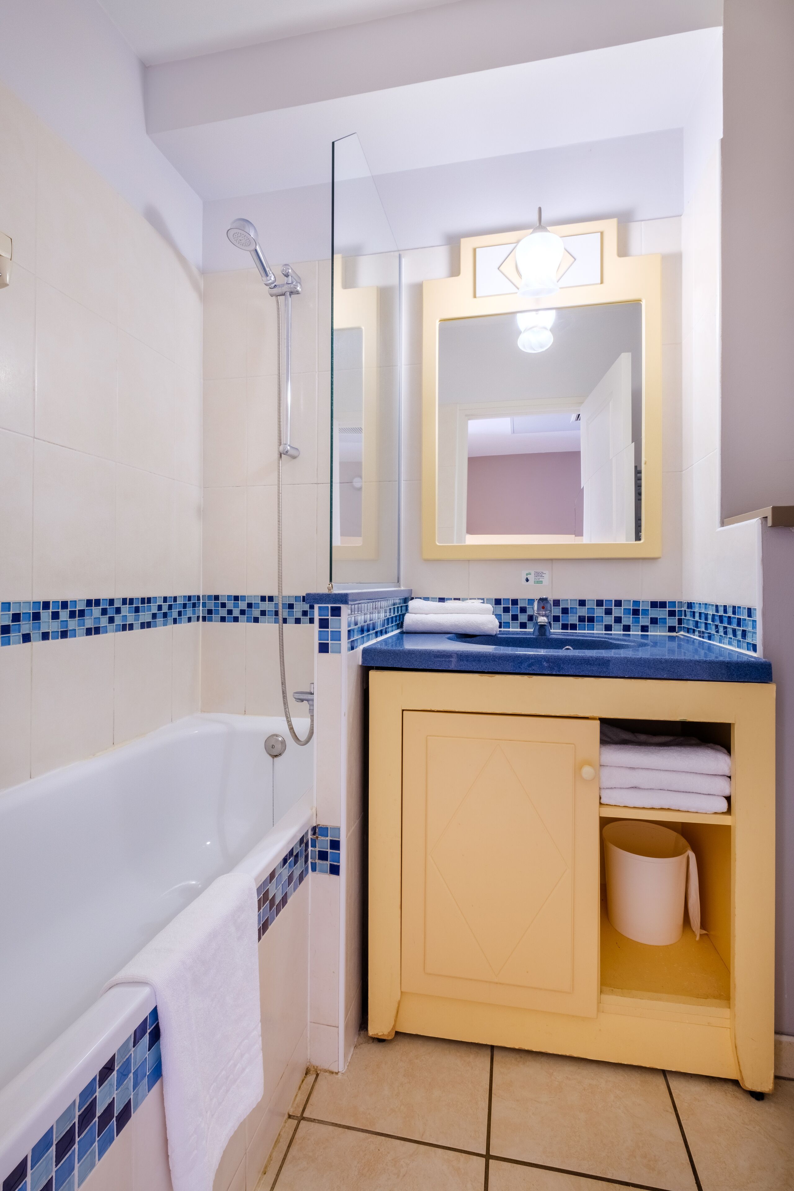 A bathroom with a bathtub, a shower, a sink with a mirror above it, and a cabinet with towels.