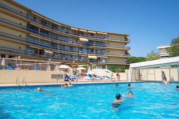 Una piscina al aire libre de temporada, sombrillas