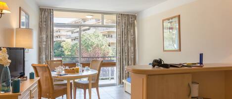 Un salon moderne avec un coin repas, de grandes fenêtres et un balcon.