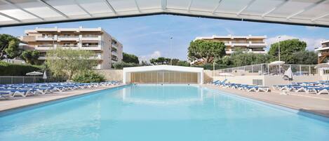 Een seizoensgebonden buitenzwembad, ligstoelen bij het zwembad