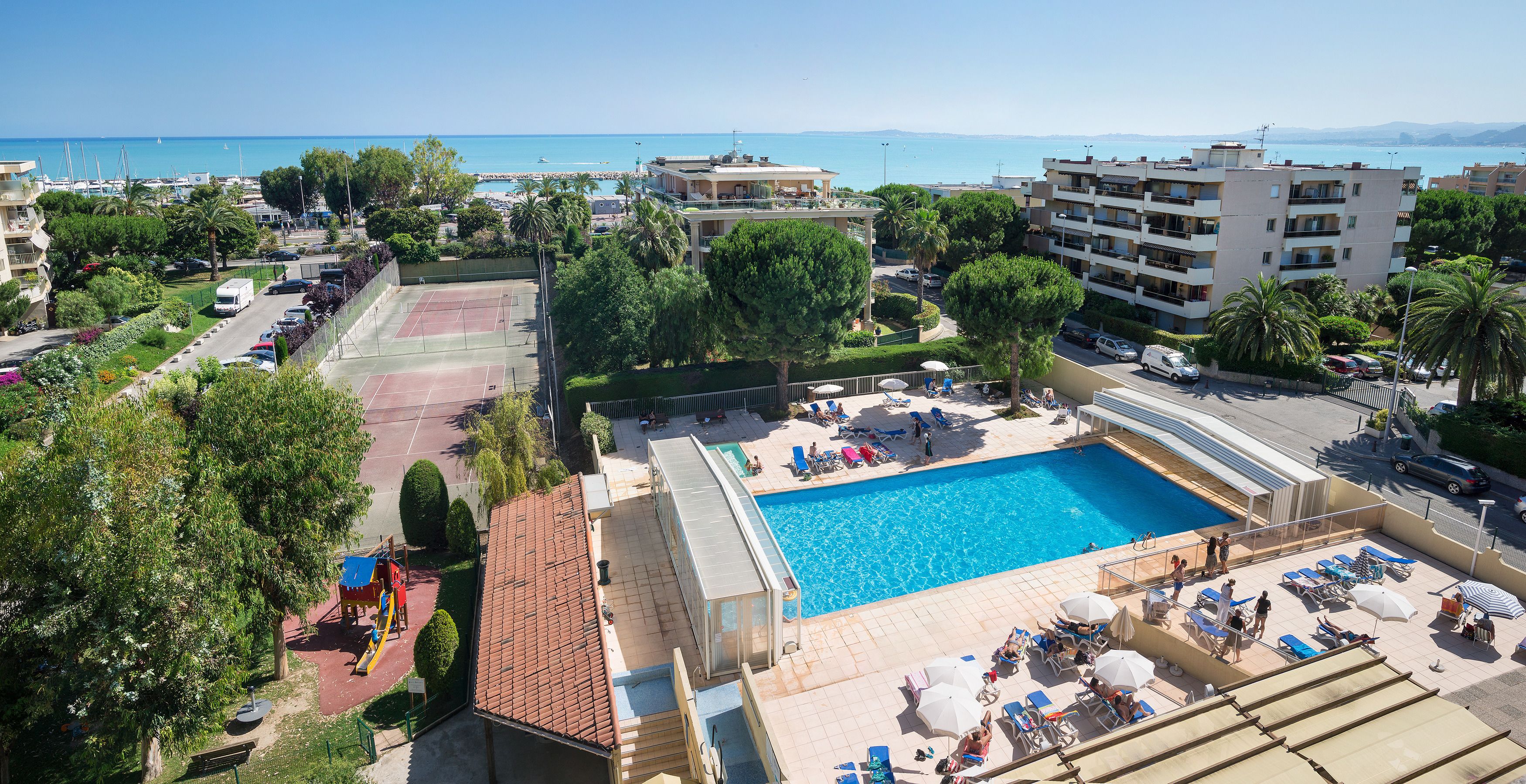 A rooftop pool with sun loungers and a tennis court.