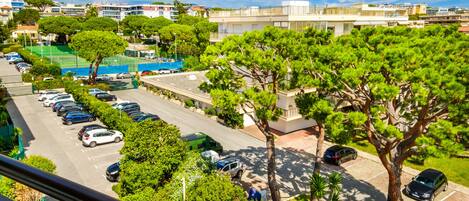 A residential area with a parking lot, trees, and buildings in the background.