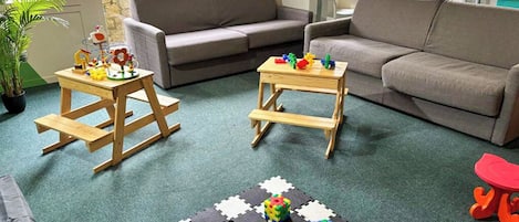 Una sala de estar con dos sofás, una mesa de centro y un tapete de juegos con juguetes.