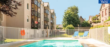 En säsongsöppen utomhuspool och solstolar