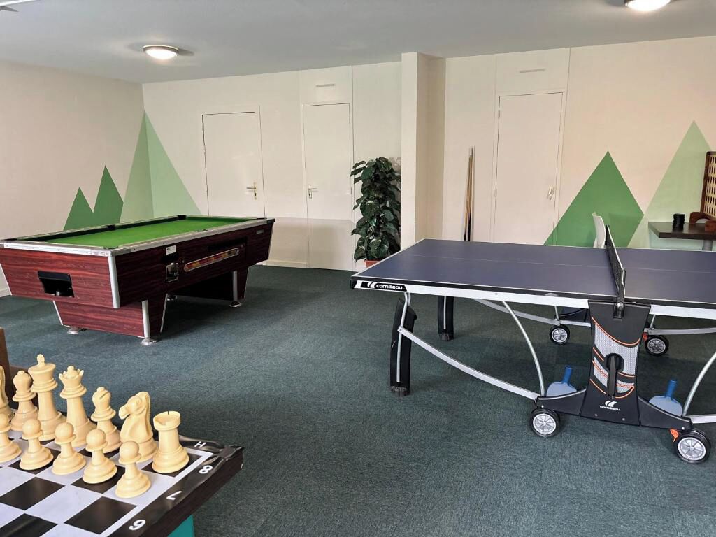 A room with a pool table, a ping pong table, and a chessboard.