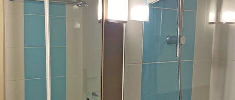 A bathroom with a white sink, a mirror, a towel rack, and a shower with a handheld showerhead.