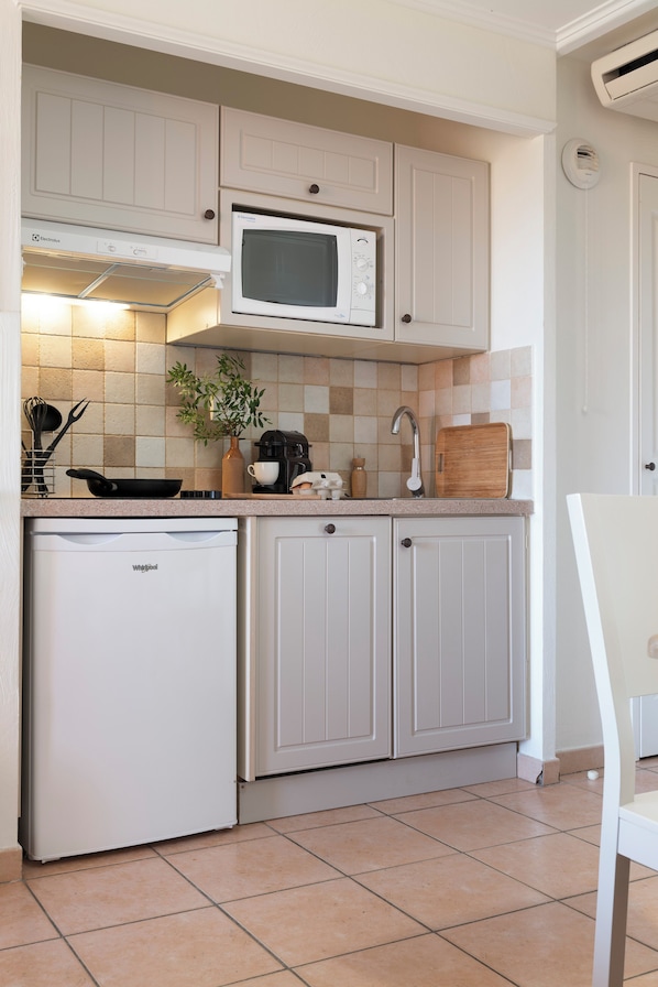 A compact kitchen with a built-in microwave, a small refrigerator, and a sink.