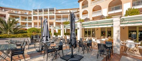 A hotel courtyard with outdoor seating, multiple balconies, and a covered area.