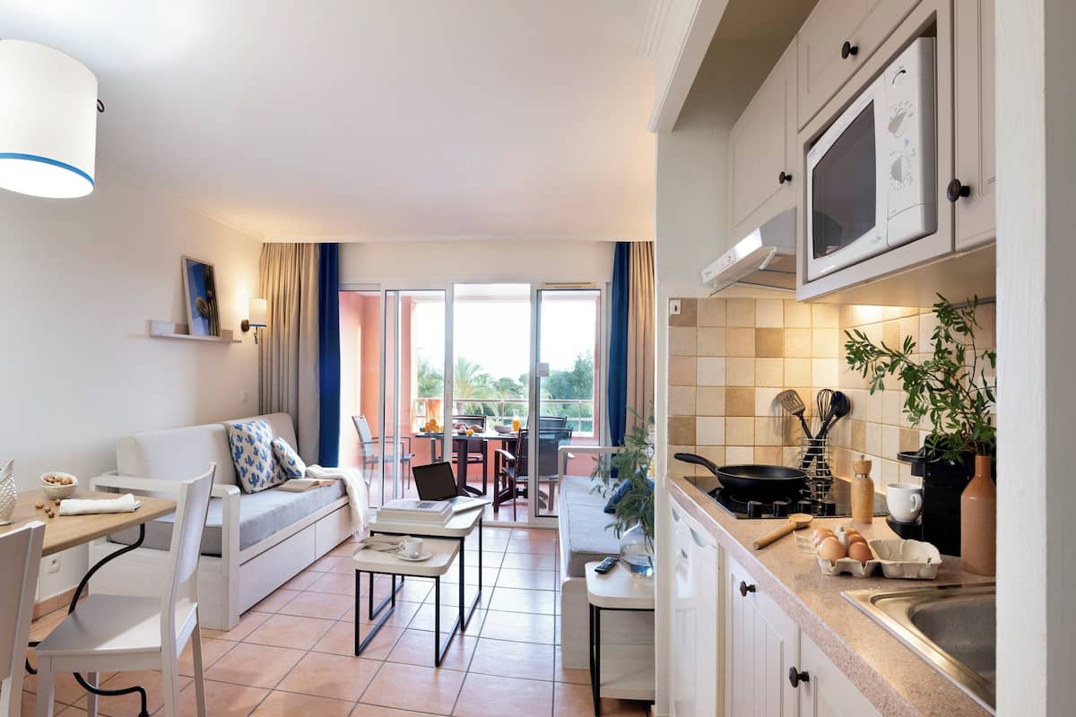 Un apartamento moderno con comedor, sofá, cocina equipada con microondas y vistas al exterior.