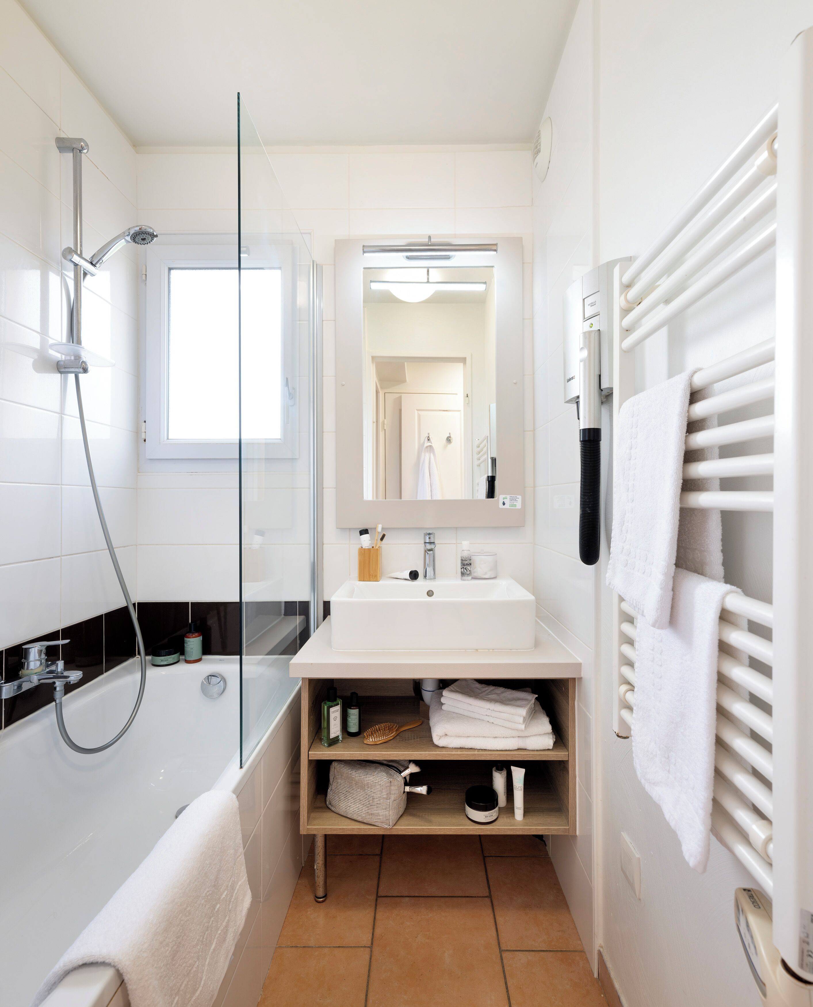 Une salle de bain moderne avec une baignoire, une douche, un lavabo blanc et un porte-serviettes.