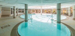 A large indoor swimming pool with clear blue water, surrounded by columns and a tiled floor. - Les Calanques (Roquebrune-sur-Argens)