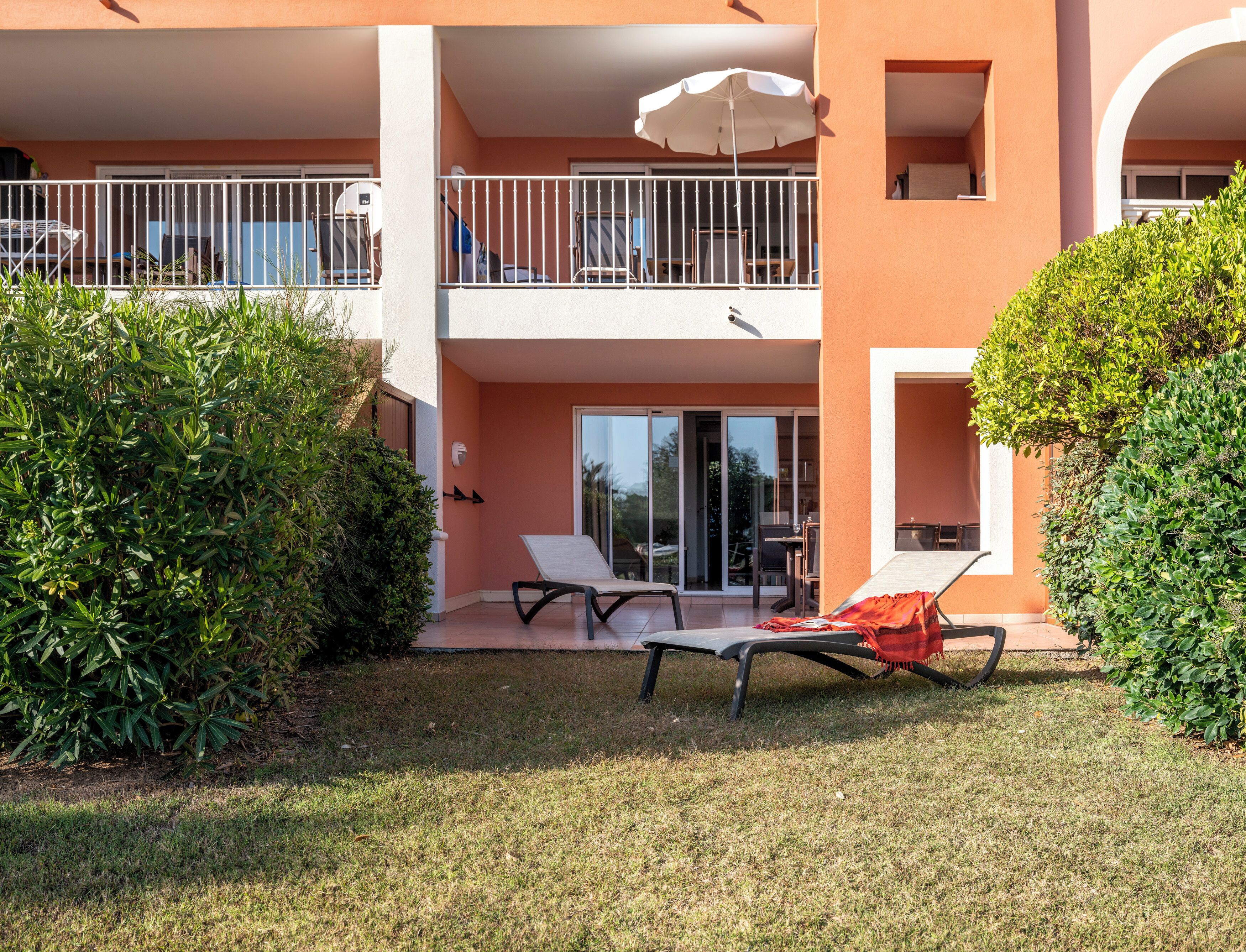 A two-story building with a balcony, a covered outdoor seating area, and a well-maintained lawn.