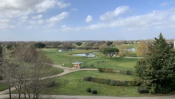 Un campo de golf con un estanque, árboles y un edificio pequeño.