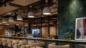 Una zona de bar con taburetes altos, una barra y una vitrina refrigerada.