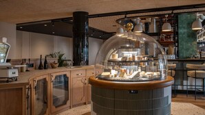 Un área de bar moderna con una vitrina central, armarios de madera y un suelo moteado.