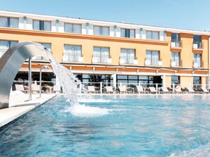 A hotel with a swimming pool, a water feature, and a row of sun loungers. - Mercure Toulouse Aeroport Golf de Seilh (Seilh)