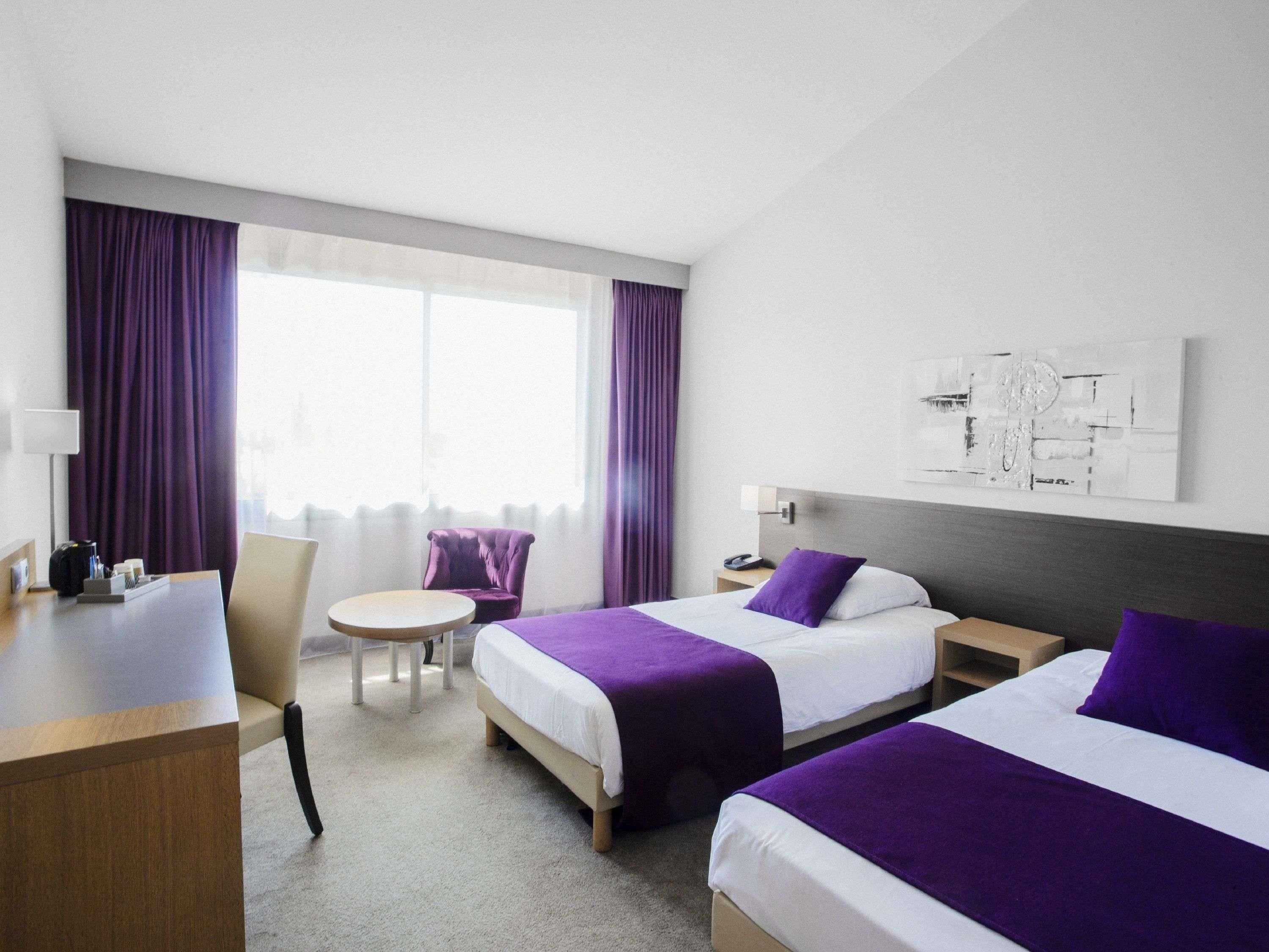 Una habitación de hotel con dos camas, un escritorio, una silla y una mesita.