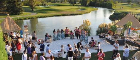 Un grupo de personas reunidas alrededor de un escenario, con un río al fondo.