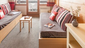 A cozy room with a sofa, a small table, and a wooden cabinet. - Pierre & Vacances Residence L'Ours Blanc (Huez)