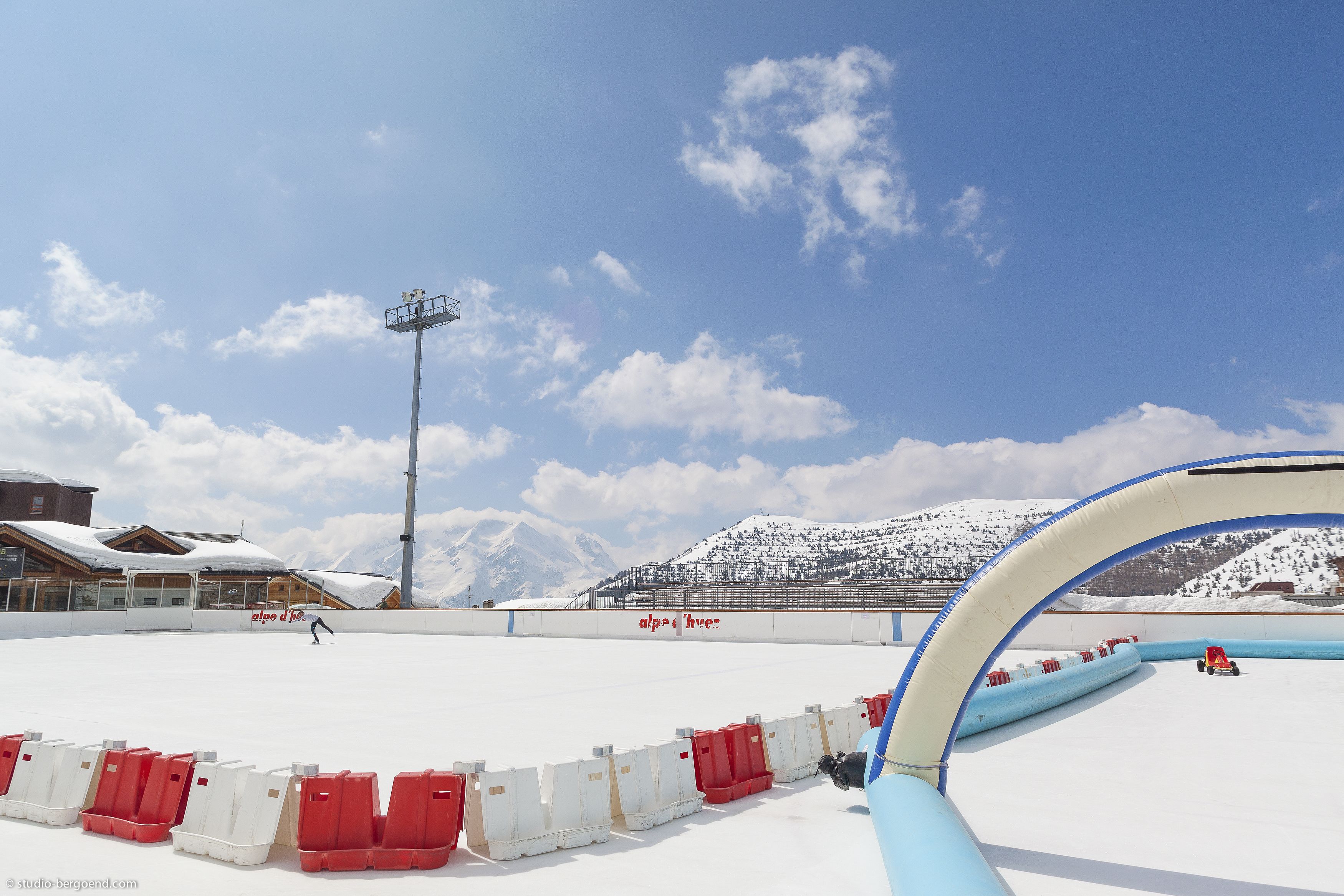 An outdoor ski slope with a clear sky, snow-covered mountains, and a ski lift in the background.