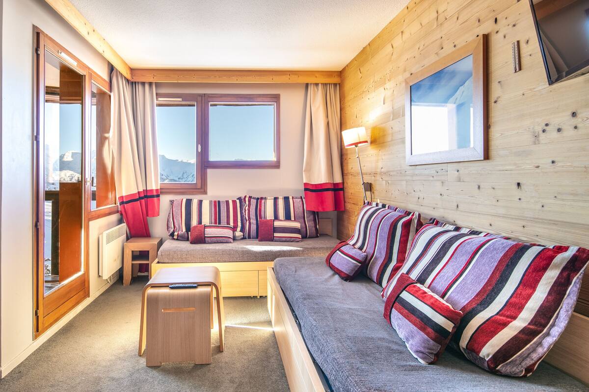 A cozy room with a bed, a sofa, a small table, and a window with curtains.