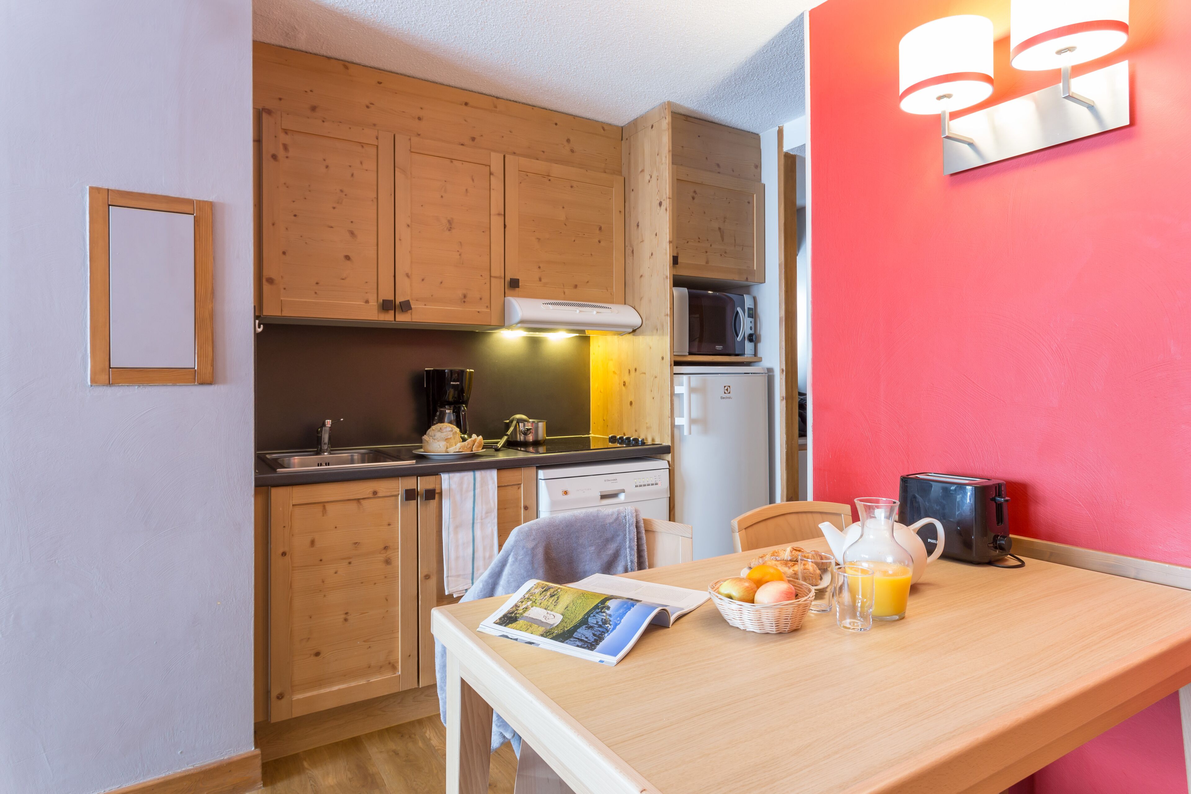A compact kitchen with wooden cabinets, a microwave, and a toaster on the countertop.