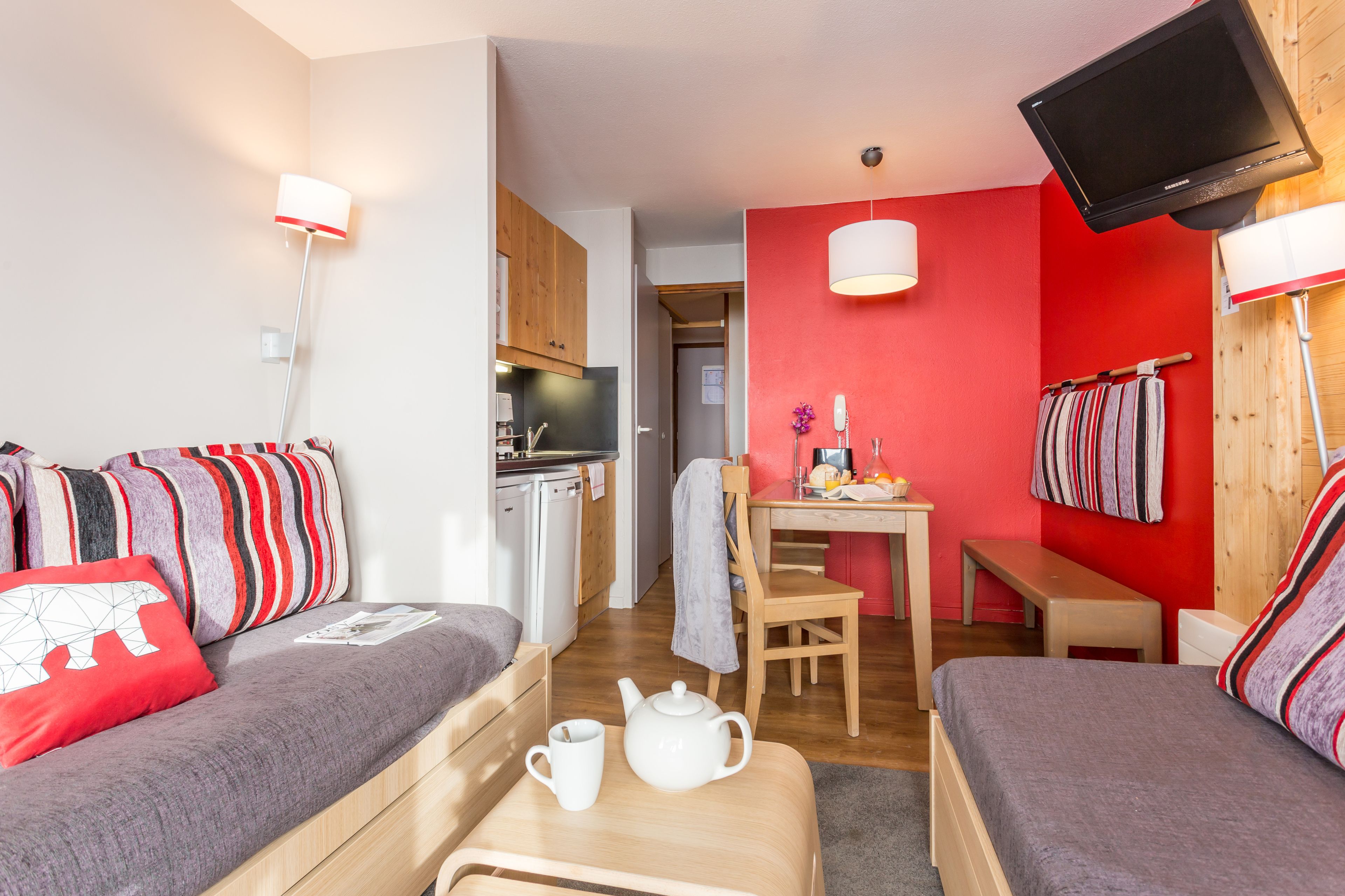 A compact room with a kitchenette, a dining area, and a sofa with striped cushions.