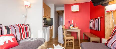 A compact room with a kitchenette, a dining area, and a sofa with striped cushions.