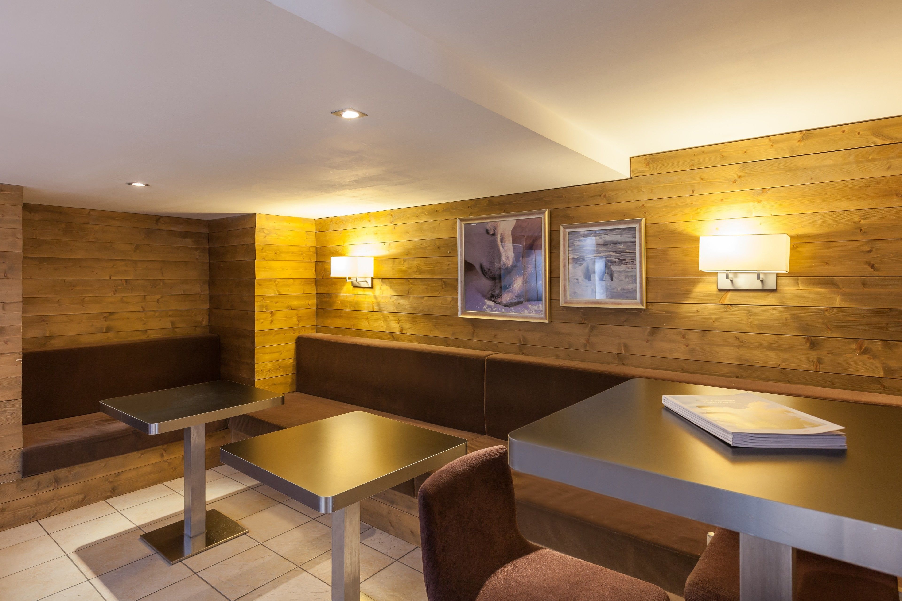 A modern interior with wooden panel walls, two tables, and benches.
