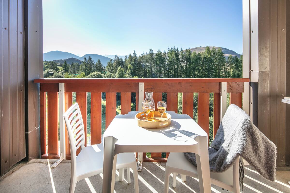 A balcony with a table, two chairs, a tray with glasses, and a blanket.