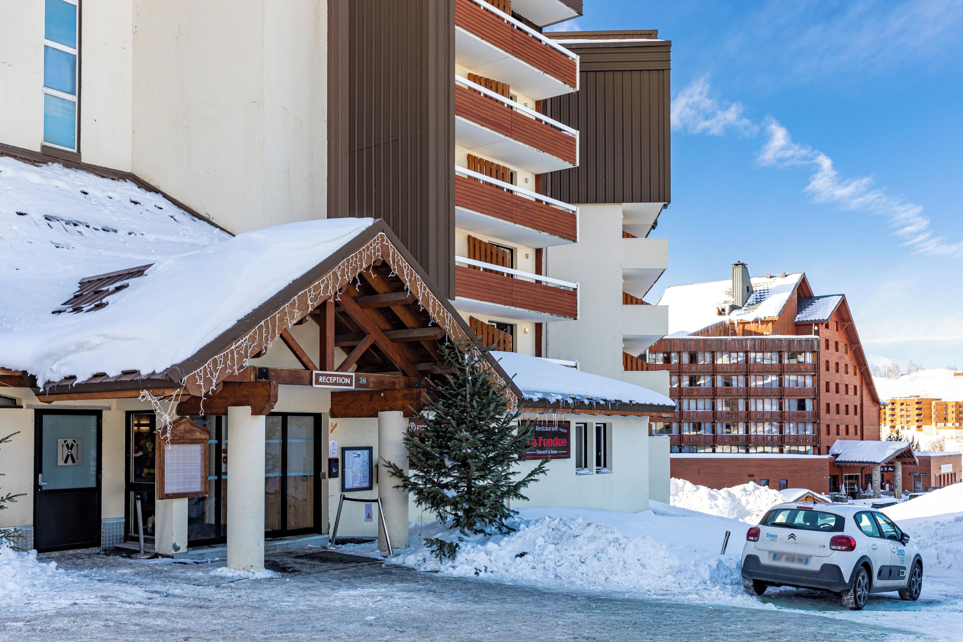 Hotel com área de recepção, árvore de Natal e um carro estacionado.