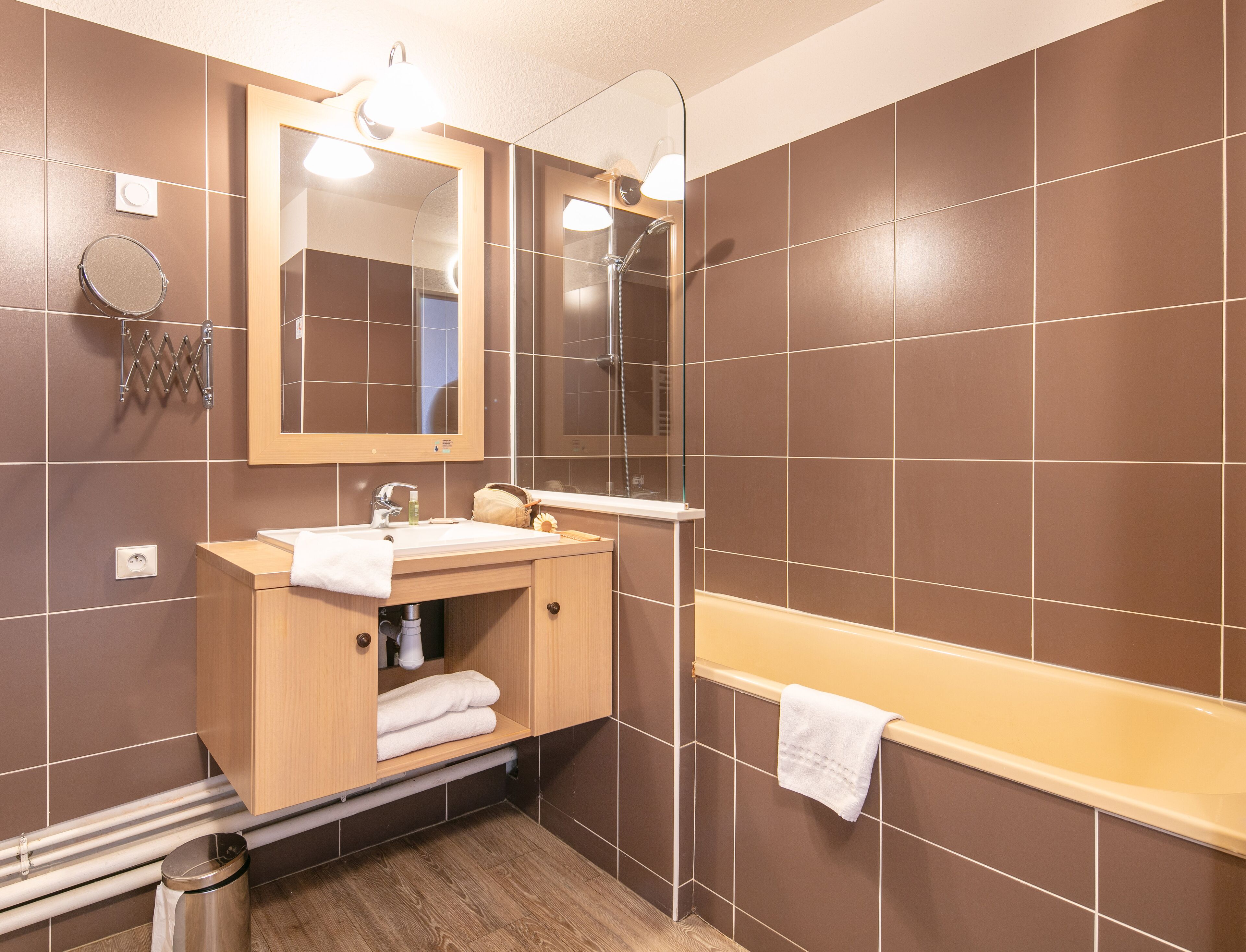 Un baño moderno con tocador de madera, un espejo grande, una bañera y zona de ducha.