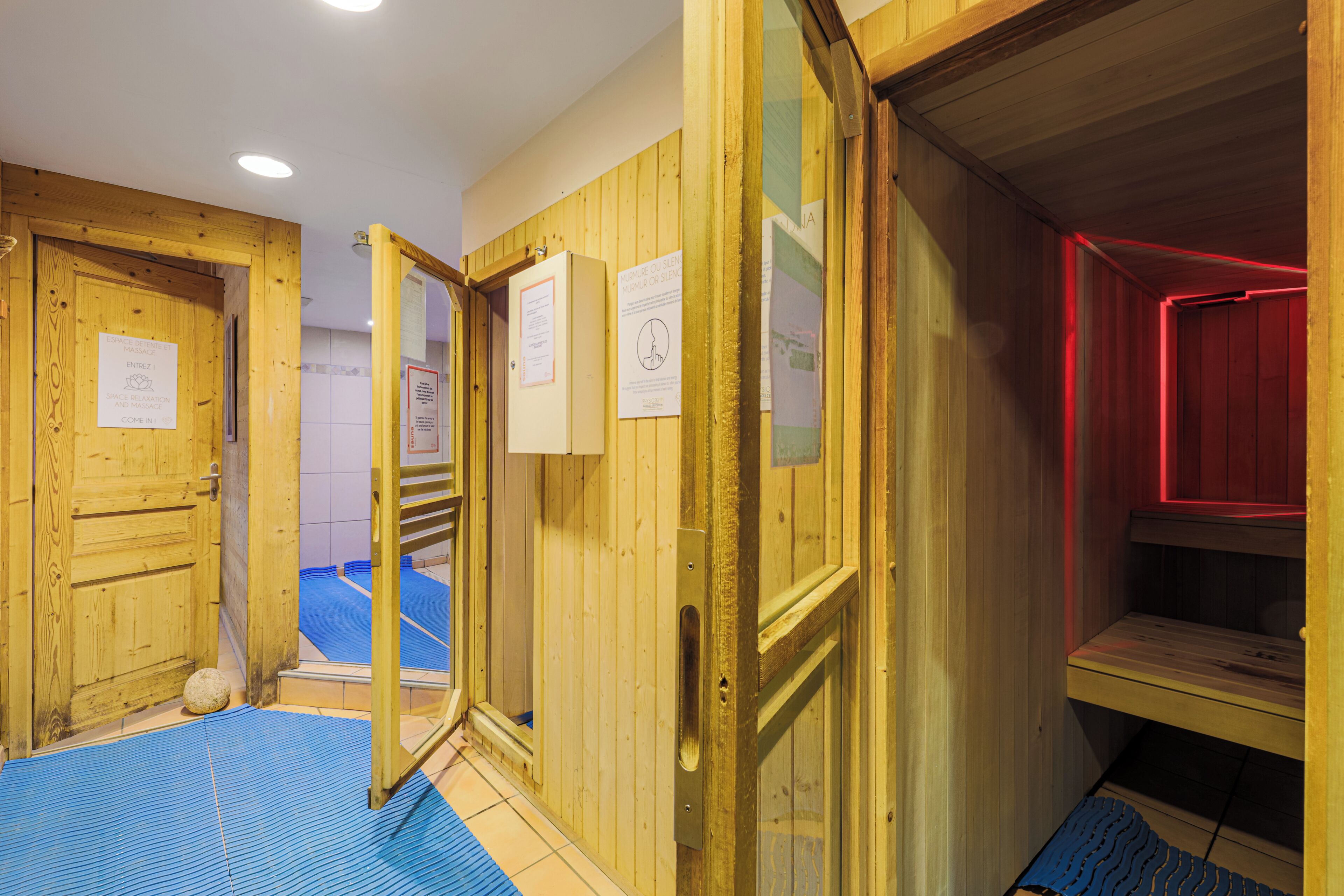 A sauna room with wooden walls, a bench, and a blue mat on the floor.