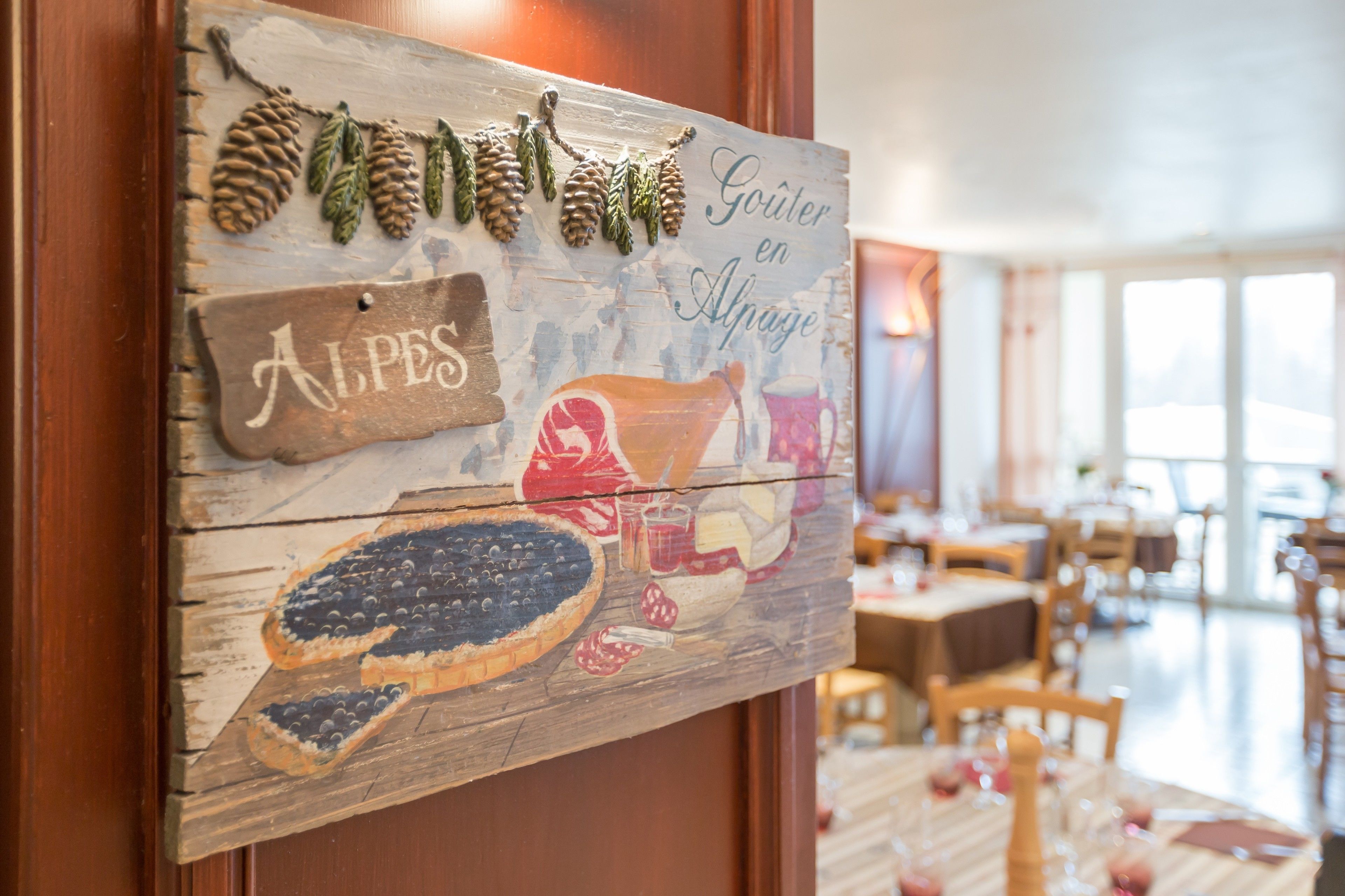 A wooden sign with food illustrations and text, likely in a dining area of a hotel.