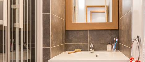 Un baño moderno con un espejo grande, un lavabo y una zona de ducha.