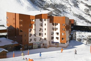 A multi-story hotel with a ski slope in the background. - Pierre & Vacances Residence Aconit (Les Belleville)