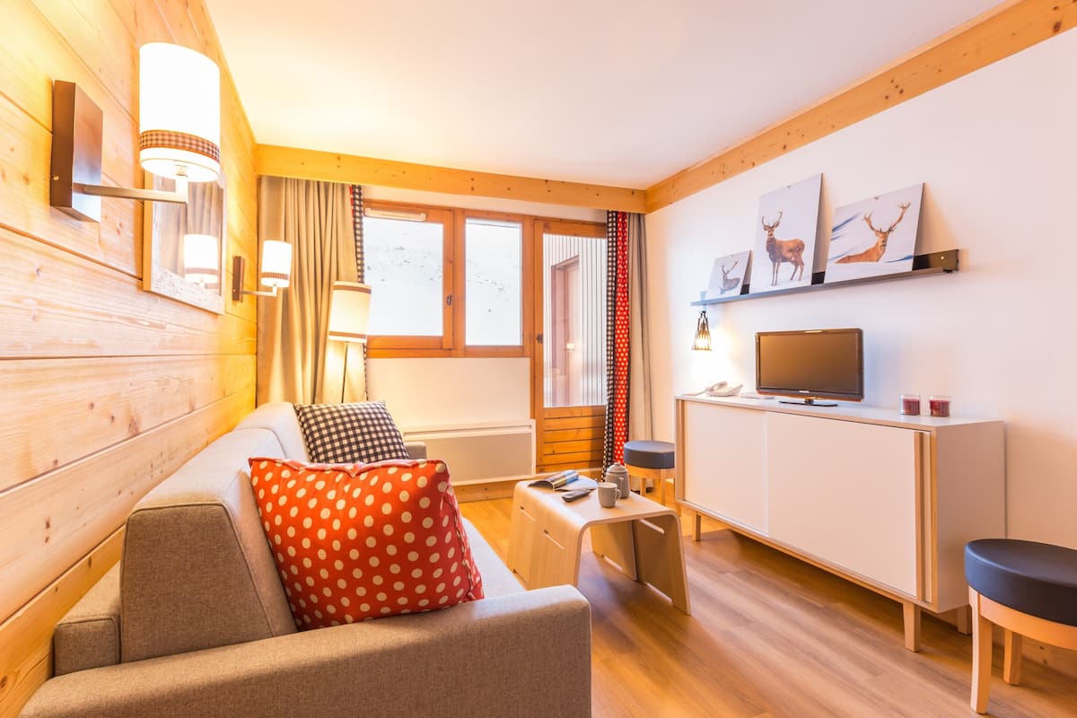 Una sala de estar acogedora con un sofá, una mesa de centro, un televisor y obras de arte en la pared.