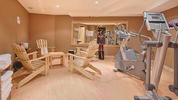 Un gimnasio con equipo de ejercicio, sillas de madera y un espejo.