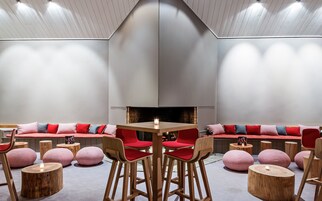 Un interior moderno con una zona de estar central, chimenea y muebles de madera.