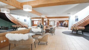 Un vestíbulo espacioso con techo de madera, asientos modernos y una escalera.