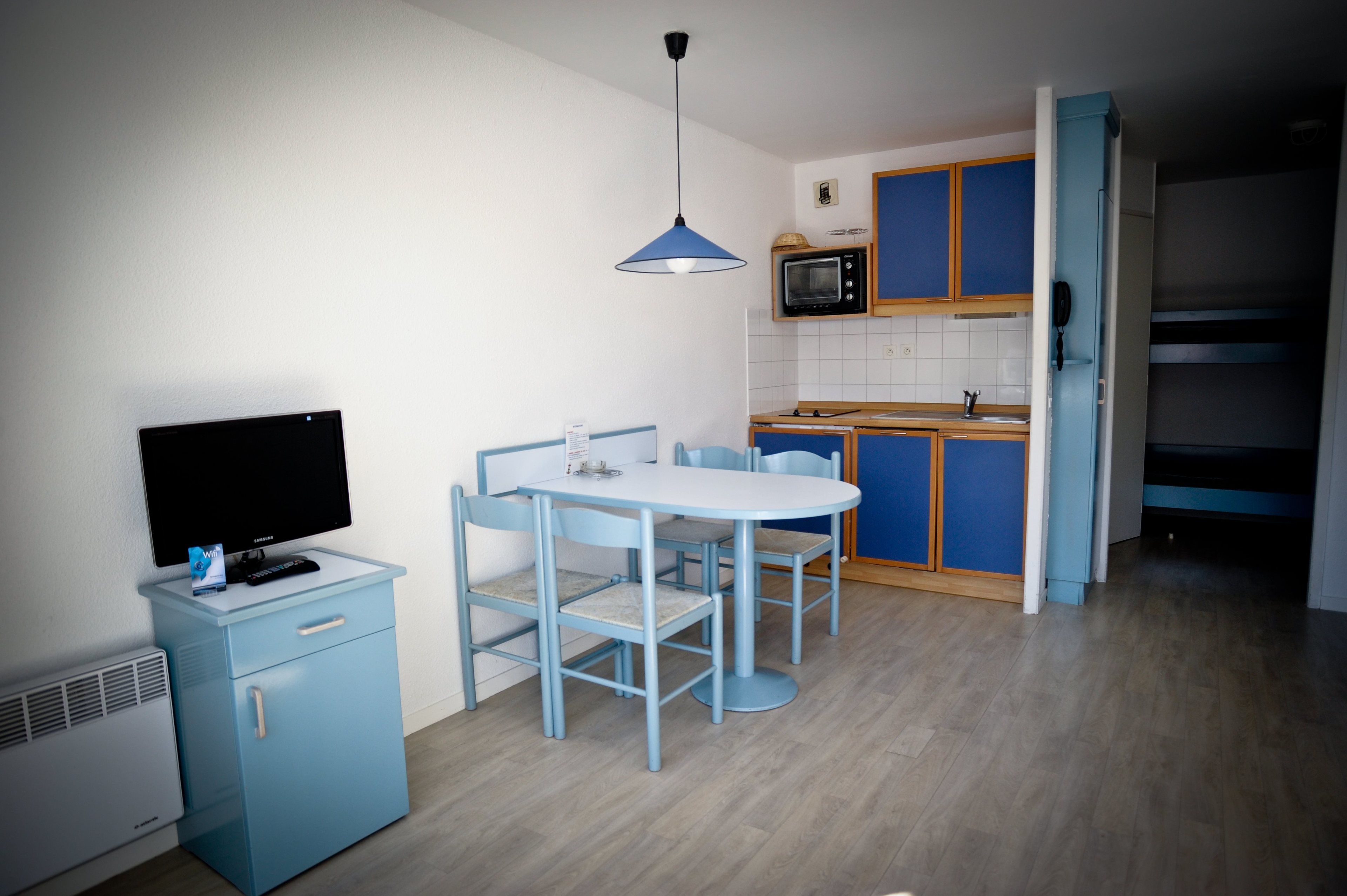 A compact kitchen with a microwave, a small refrigerator, and a dining area with a table and chairs.